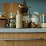 Organized kitchen counter with glass jars of grains, pasta, and spices.