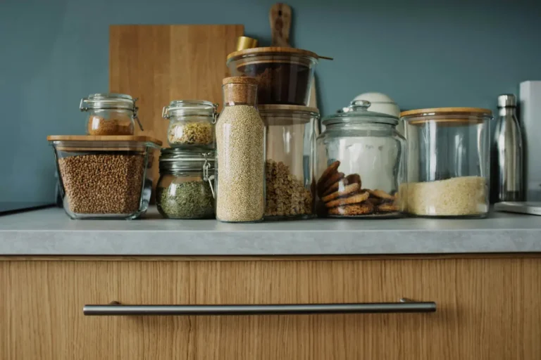 Organized kitchen counter with glass jars of grains, pasta, and spices.
